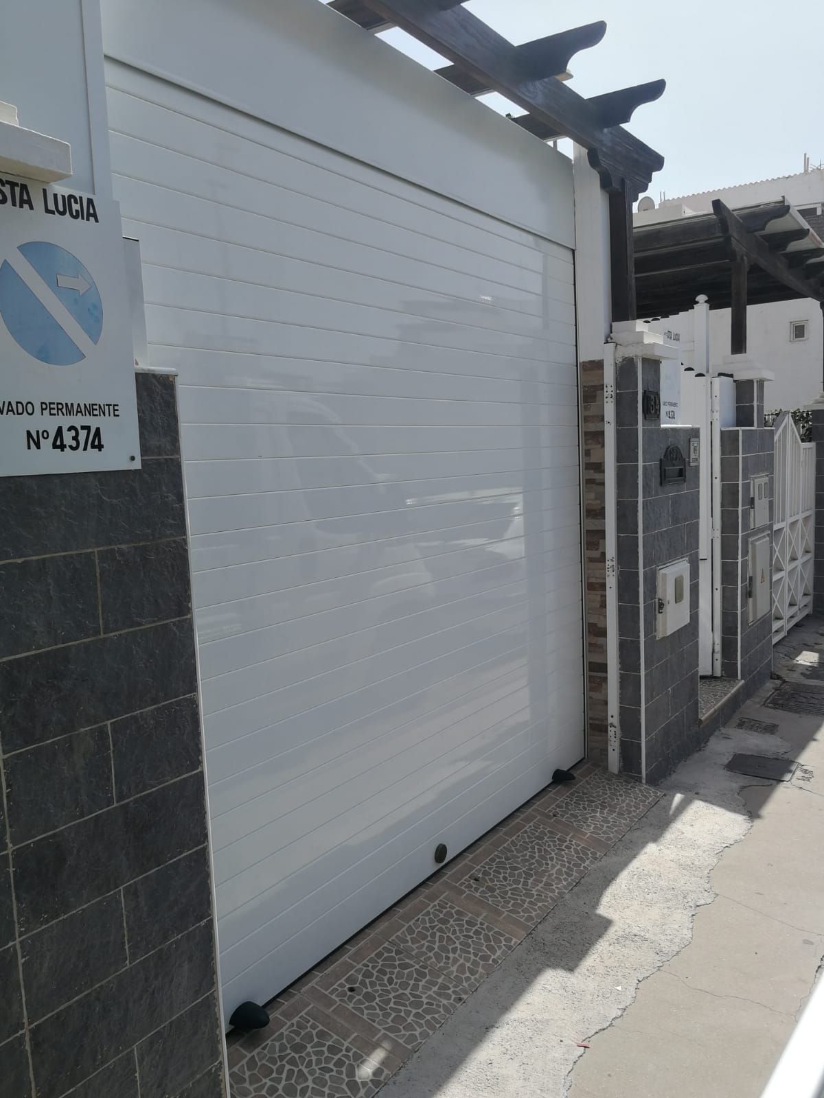 Una puerta de garaje corrediza blanca con un cartel que dice 'Avenida Lucía'.