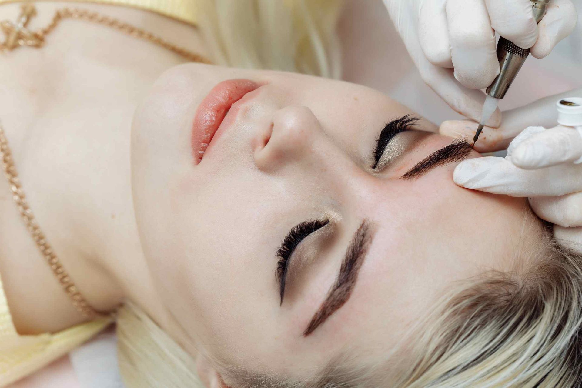 Una mujer se está maquillando permanentemente las cejas.