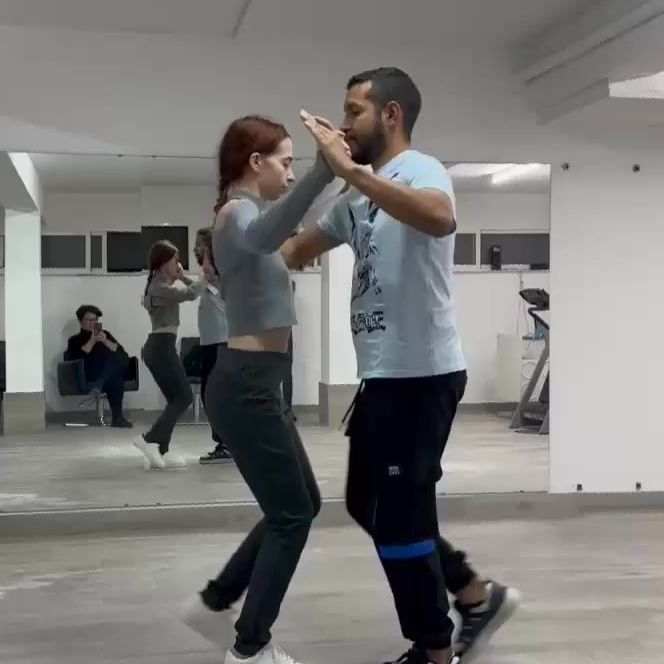 Un hombre y una mujer bailan frente a un espejo.