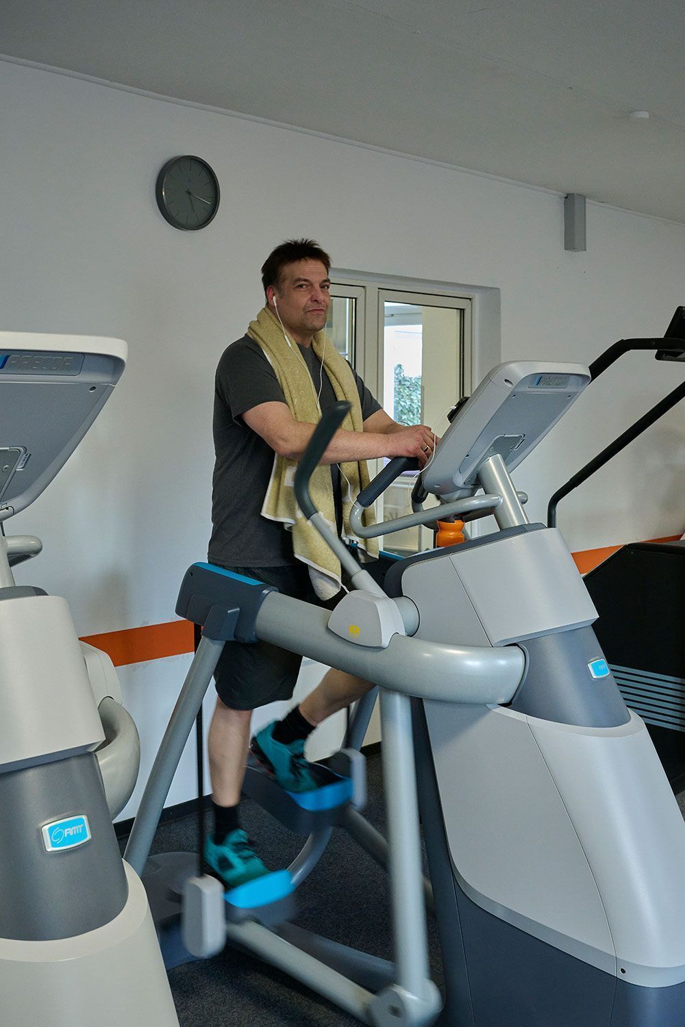 Ein Mann fährt in einem Fitnessstudio auf einem Crosstrainer.