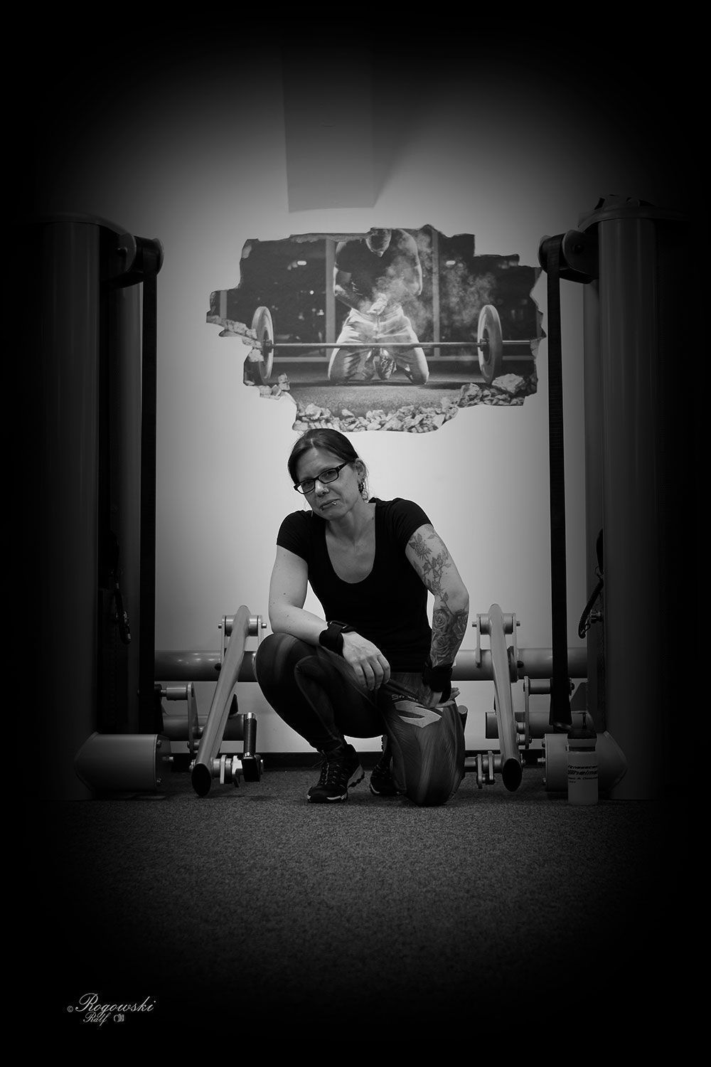 Ein Schwarzweißfoto einer Frau, die in einem Fitnessstudio hockt.