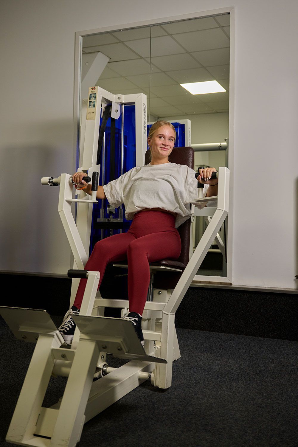 Eine Frau sitzt in einem Fitnessstudio auf einem Gerät.