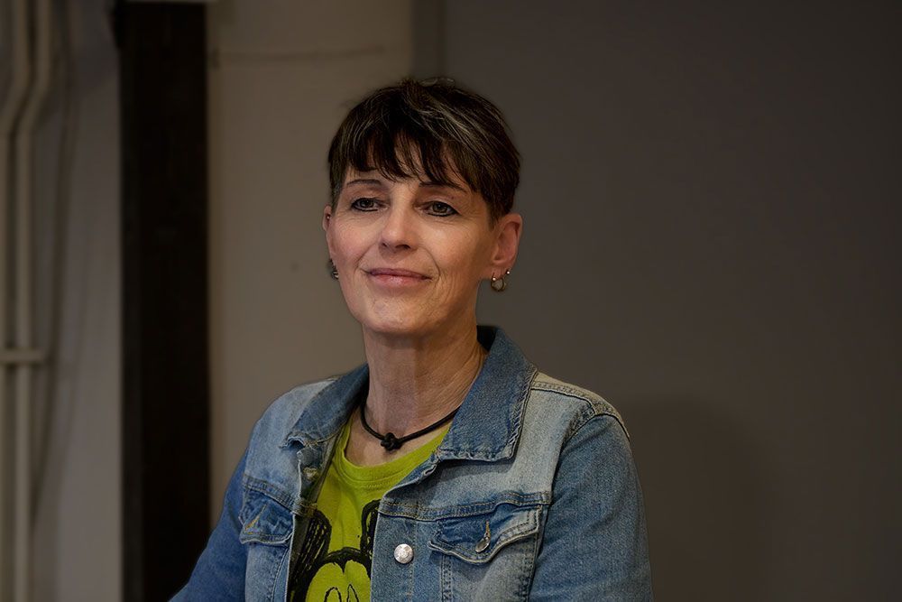 Eine Frau trägt eine Jeansjacke und ein grünes Hemd.