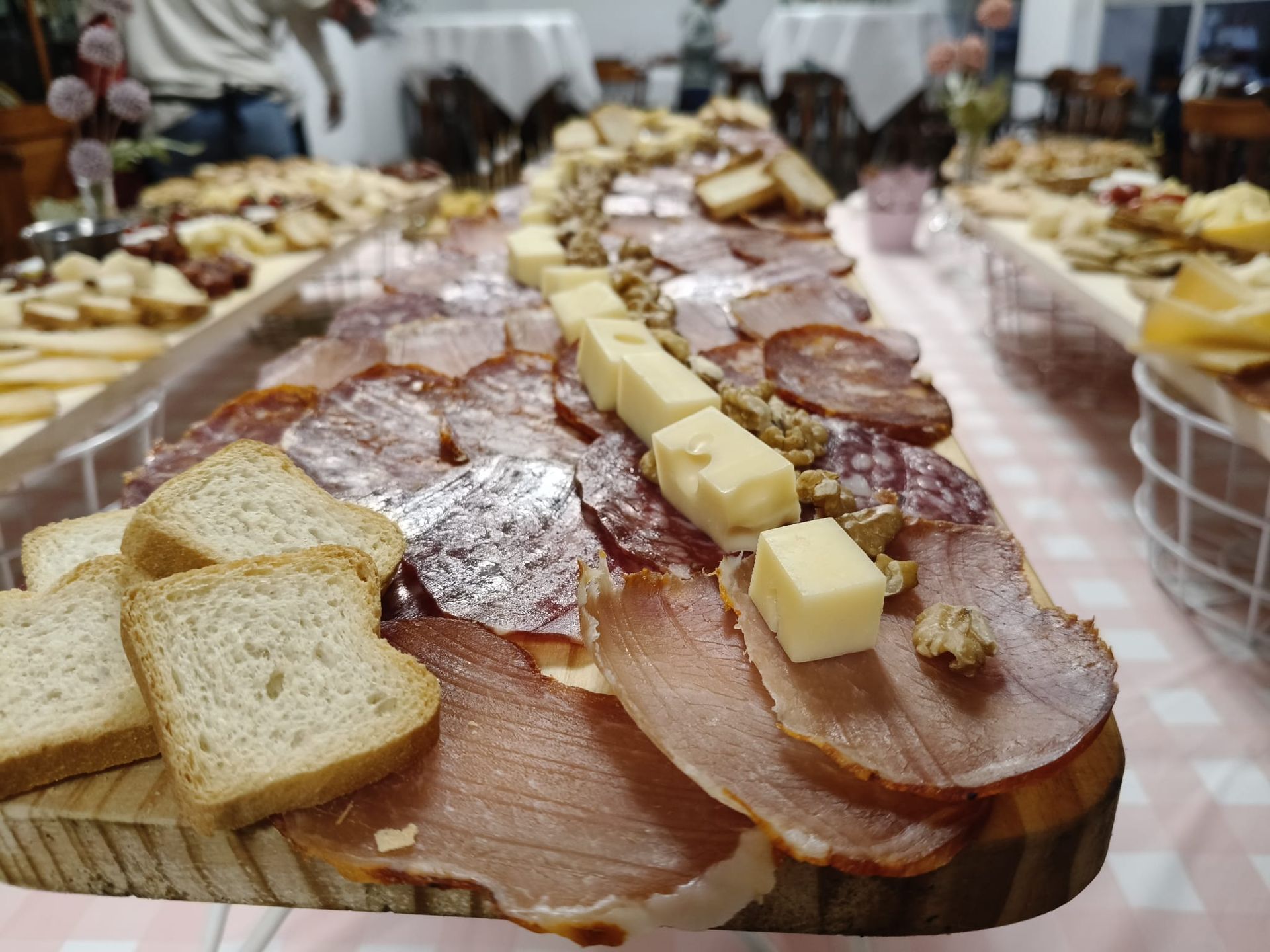 Una tabla de cortar de madera llena de queso, uvas y un gran surtido de ibéricos.