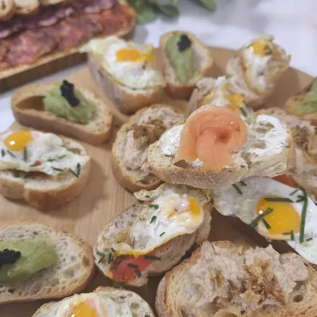 Una tabla de cortar de madera cubierta con una variedad de sándwiches.
