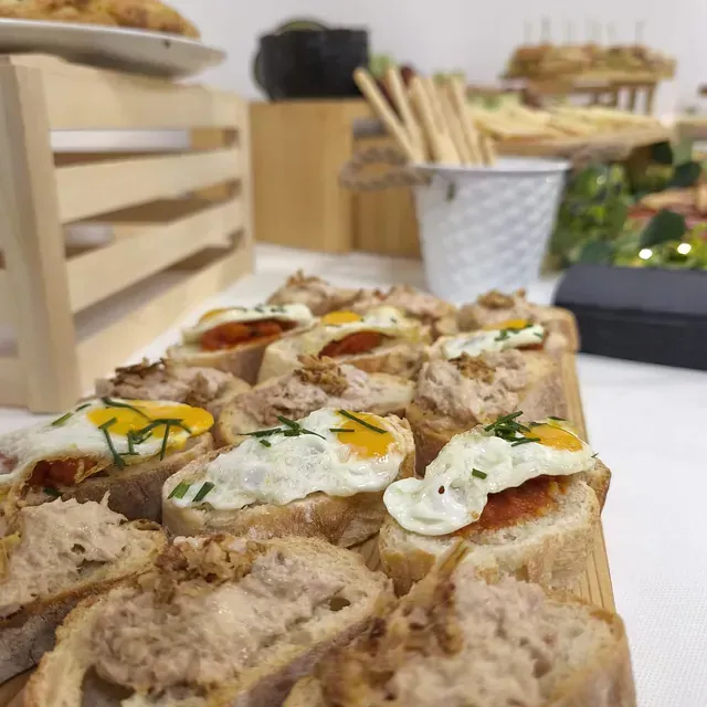 Un montón de sándwiches en una tabla de cortar de madera sobre una mesa.