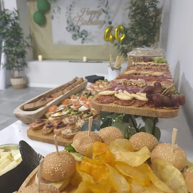 Una mesa llena de comida con una pancarta de feliz cumpleaños en el fondo.