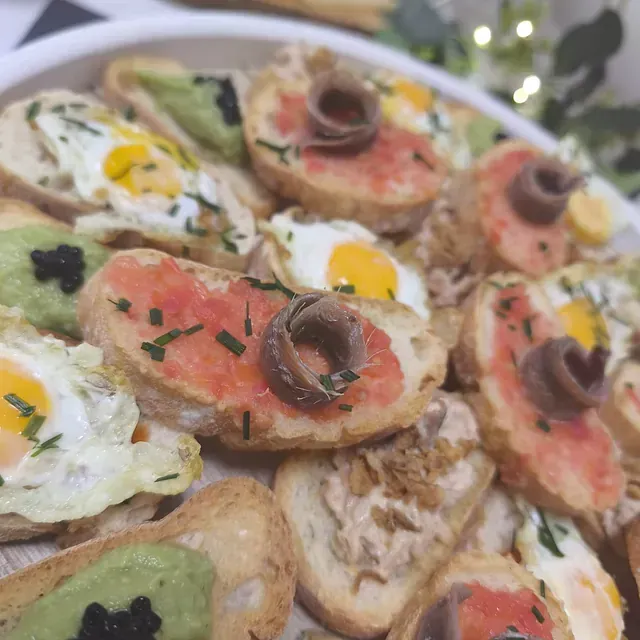 Un primer plano de un plato de comida con huevos y anchoas encima.