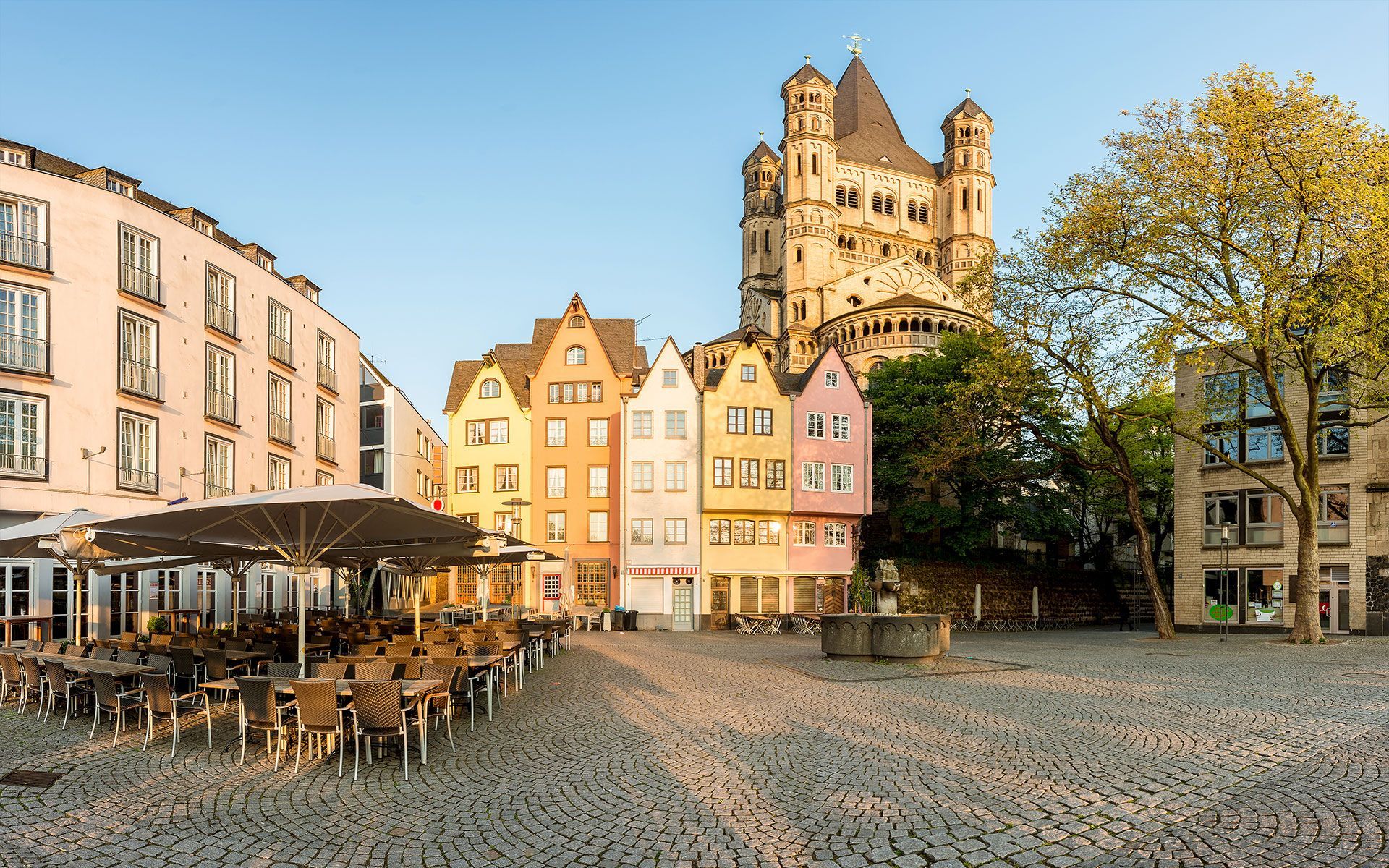 Eine Reihe von bunten Gebäuden mit einem großen Turm dahinter in Köln
