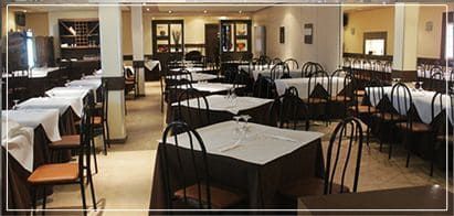 Comedor del restaurante con mesas preparadas para los comensales. Las mesas tienen manteles blancos.