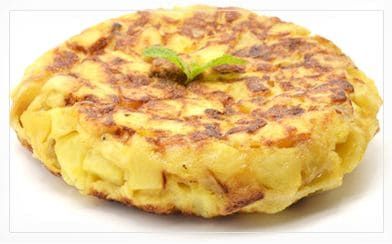 Tortilla de patatas con el exterior dorado, adornada con una ramita de menta.