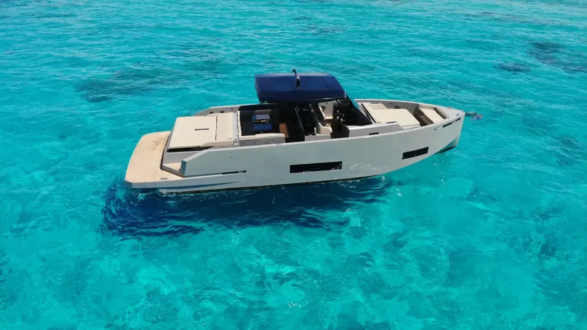 Yate a motor blanco sobre aguas de color turquesa brillante con toldo azul oscuro.