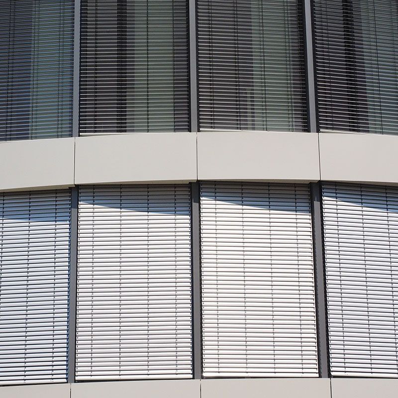 Eine Nahaufnahme eines Gebäudes mit vielen Fenstern und Jalousien.