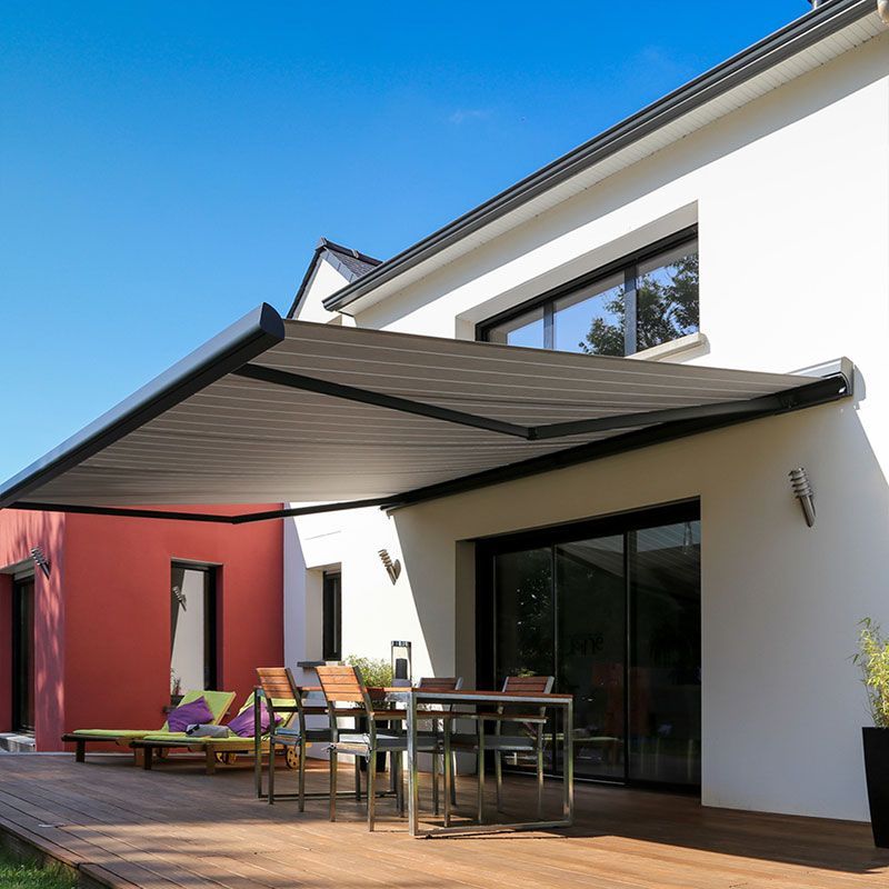 Ein weißes Haus mit einer großen Markise über der Terrasse