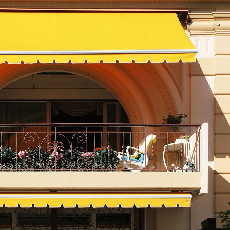 Ein Balkon mit einer gelben Markise darüber
