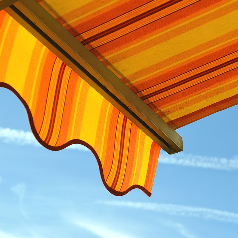 Eine orange und gelb gestreifte Markise vor einem blauen Himmel
