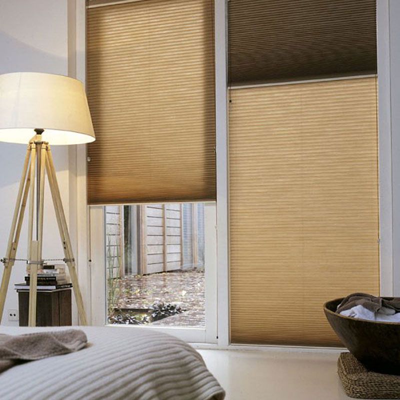 Ein Schlafzimmer mit einem Bett, einer Lampe und einem Fenster mit Jalousien