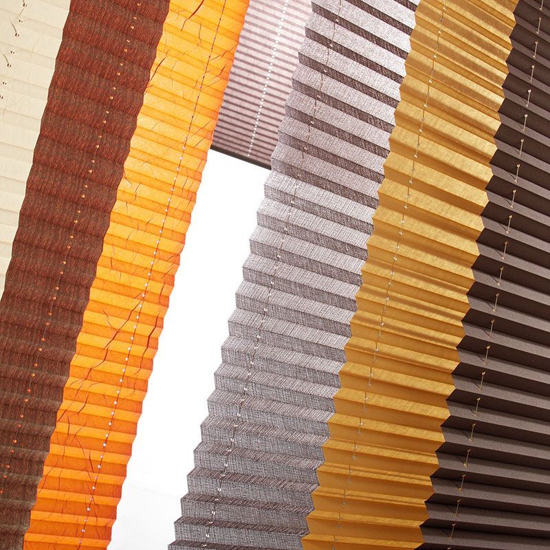 Eine Reihe verschiedenfarbiger Plissees an einem Fenster