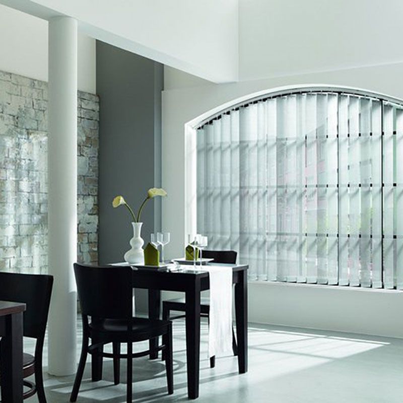 Ein Esszimmer mit Tisch und Stühlen und einem Fenster mit vertikalen Jalousien