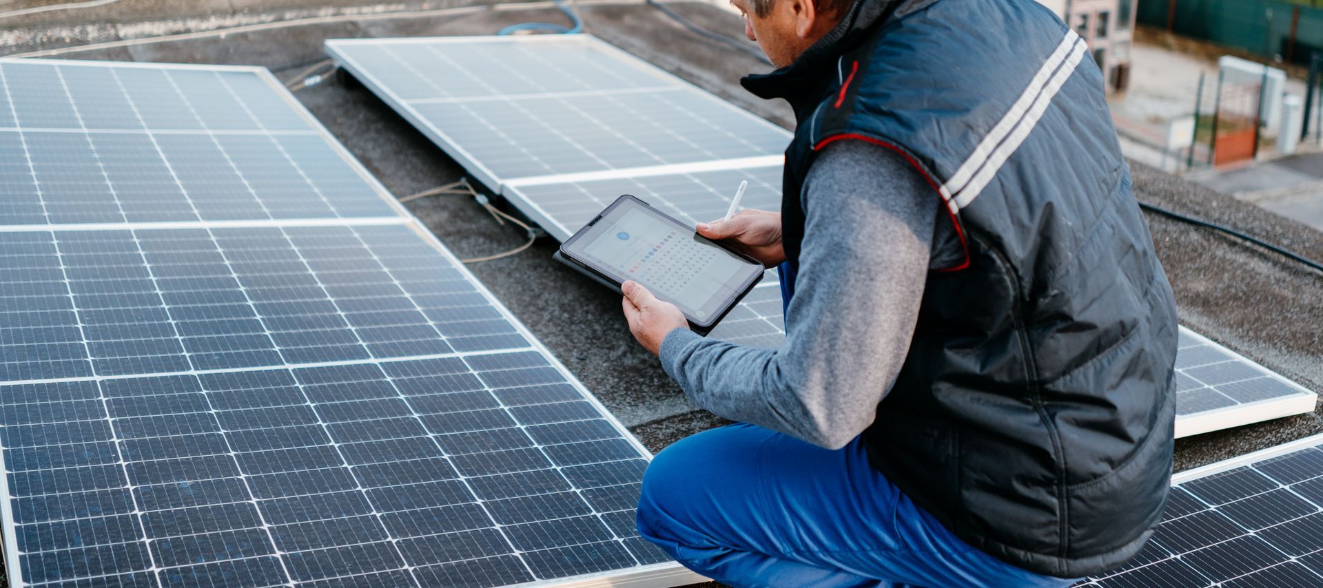 Technicien avec une tablette devant des panneaux solaires