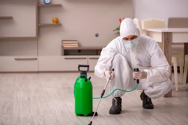 Un hombre con un traje de protección está rociando una habitación con un pulverizador.