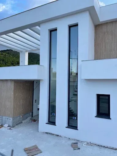 Exterior de una casa blanca moderna, con ventanas altas y estrechas y una entrada cubierta en construcción