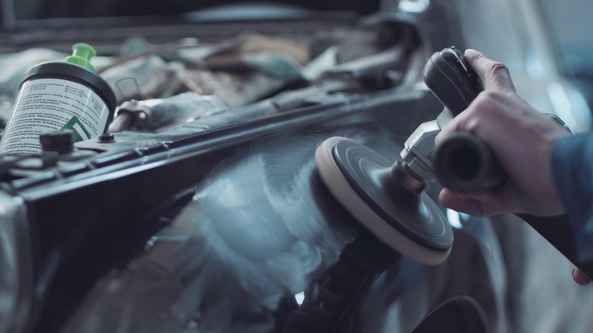 Un mécanicien utilise une polisseuse rotative pour rénover la carrosserie d'une voiture.