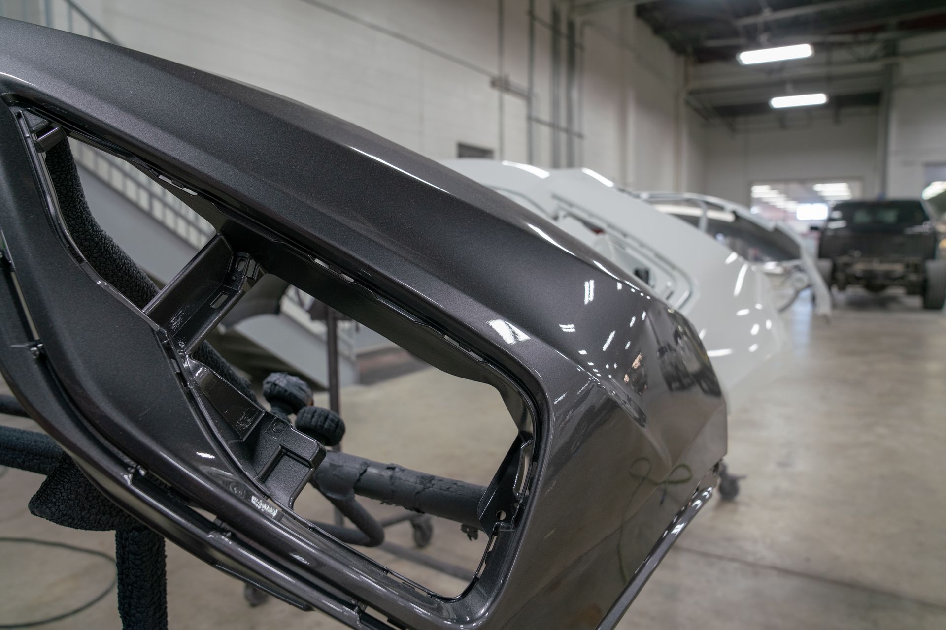 Gros plan sur un élément de carrosserie noir dans un atelier automobile.