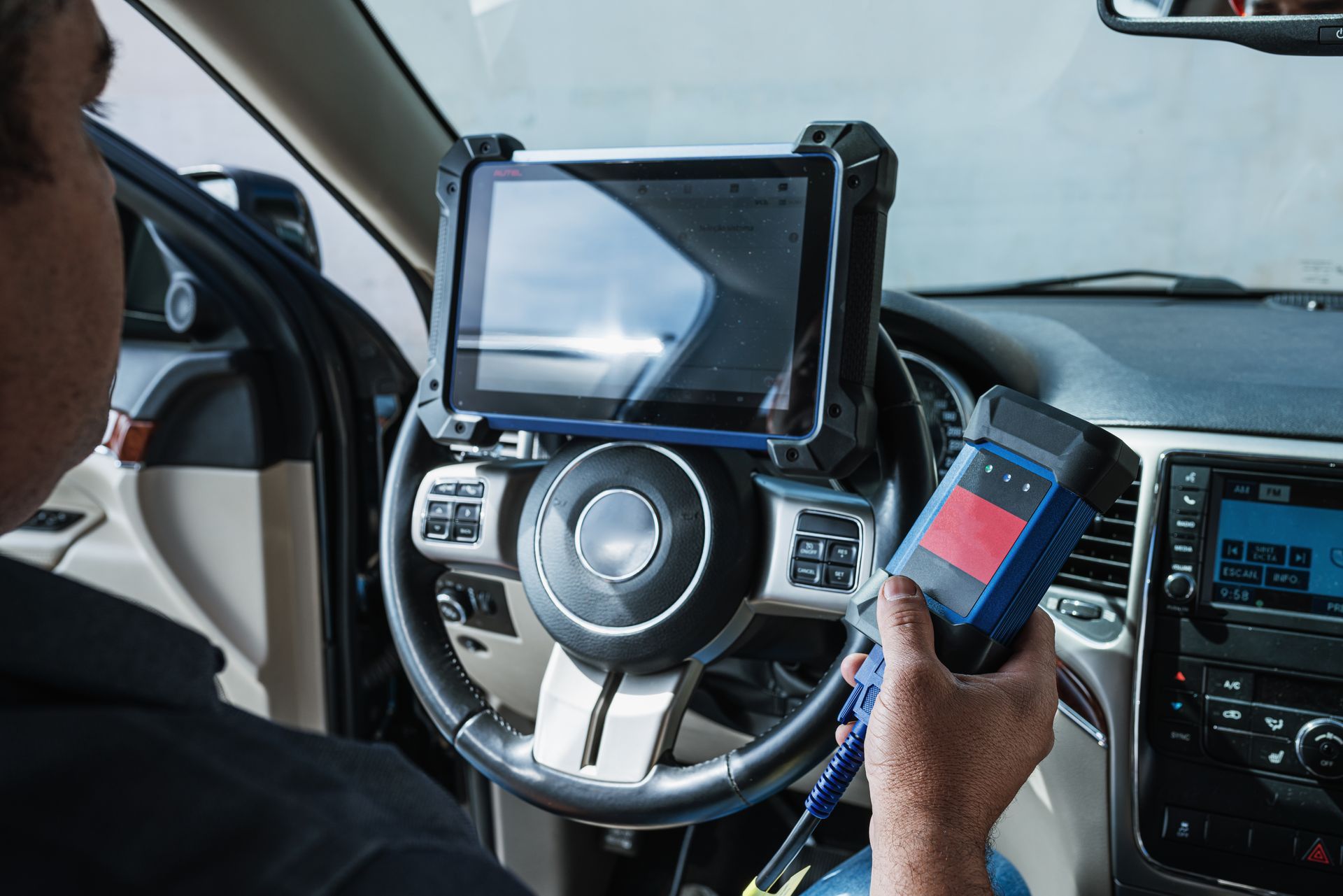 Un garagiste réalise un diagnostic automobile au volant d'une voiture.