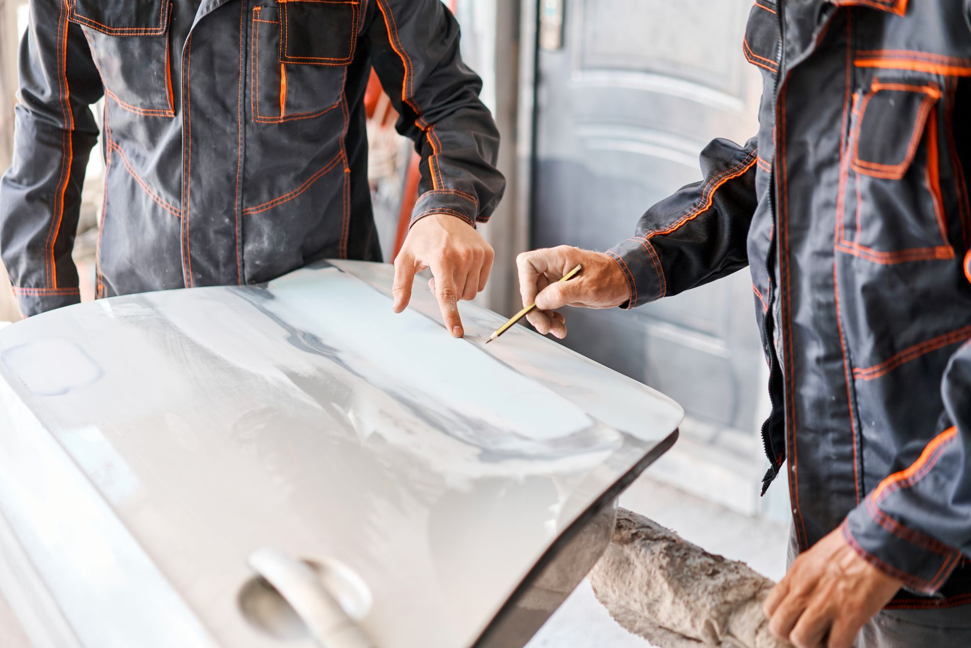 Des garagistes inspectent un élément de carrosserie.