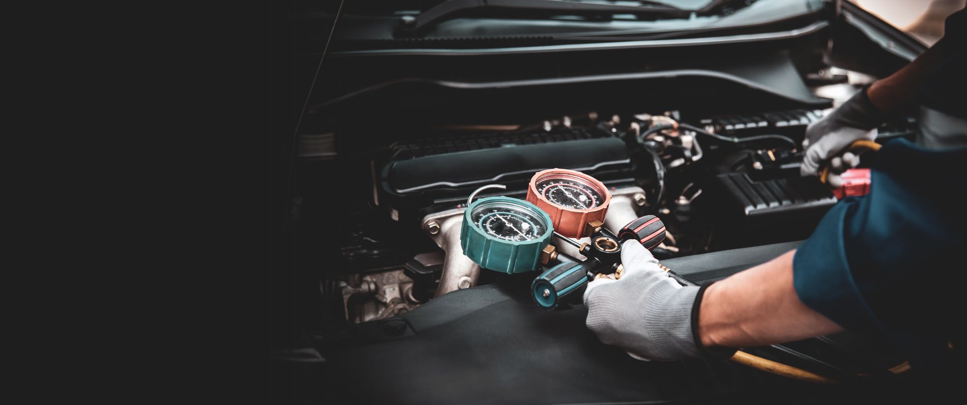 Un garagiste utilise un manomètre pour vérifier le niveau de réfrigérant d'une voiture.