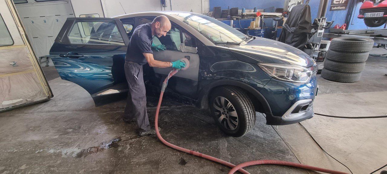 Un garagiste répare la carrosserie d'une voiture dans son atelier.