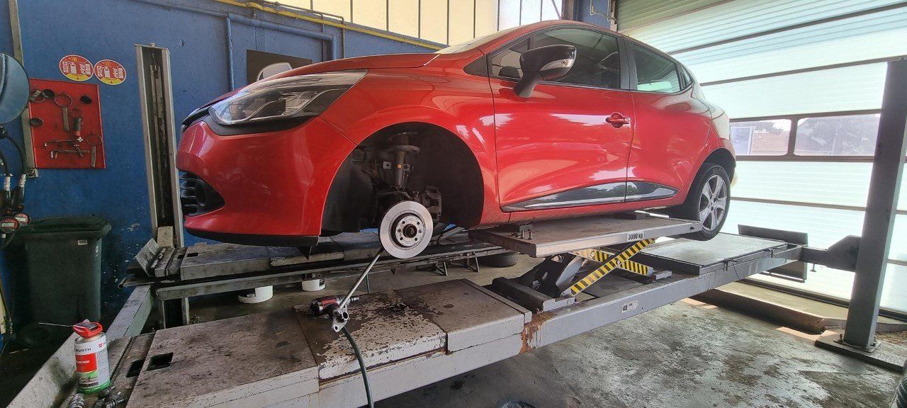 Une voiture rouge sur un pont élévateur dans un garage automobile.