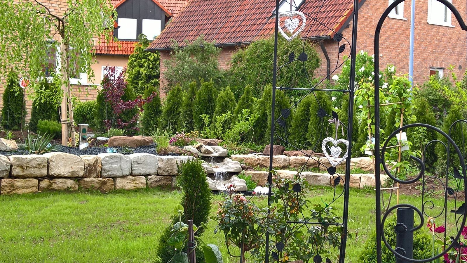 Blick in einen bepflanzten Garten mit Natursteinmauern