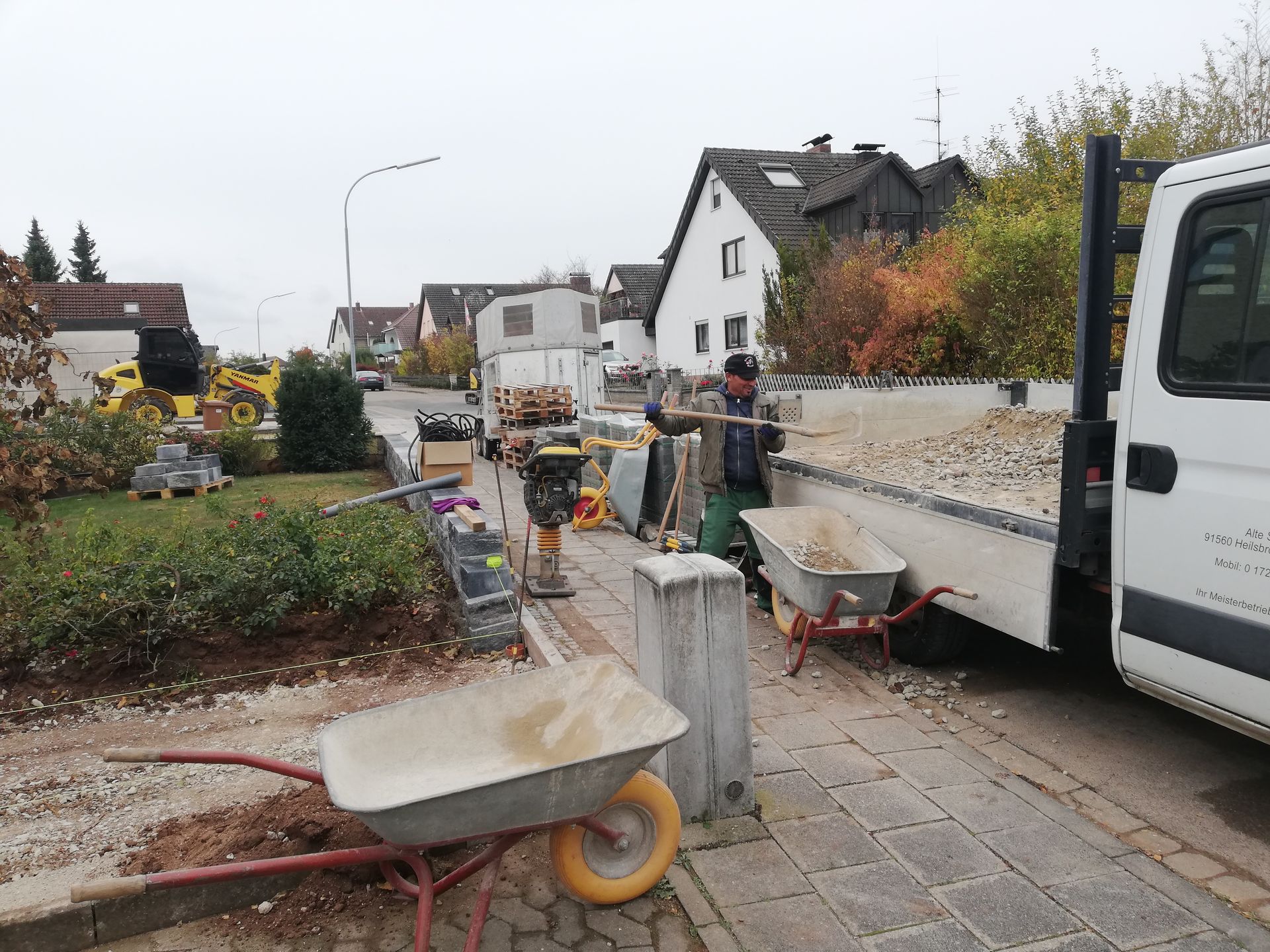 ein Bauarbeiter arbeitet im Vorgarten eines Hauses