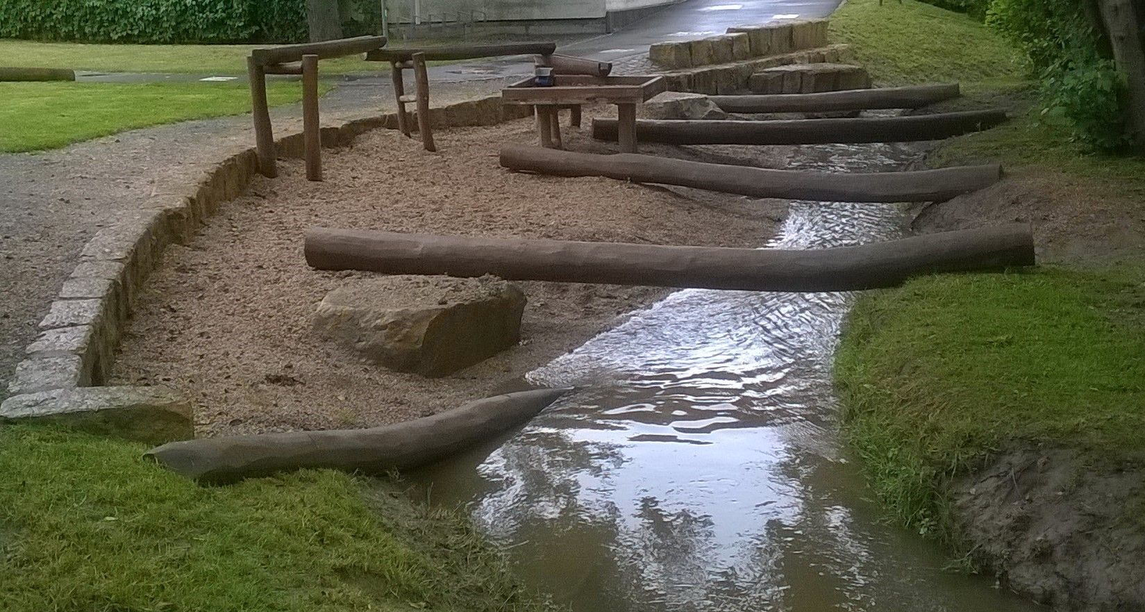 einzelne Baumstämme liegen über einem kleinen Bach