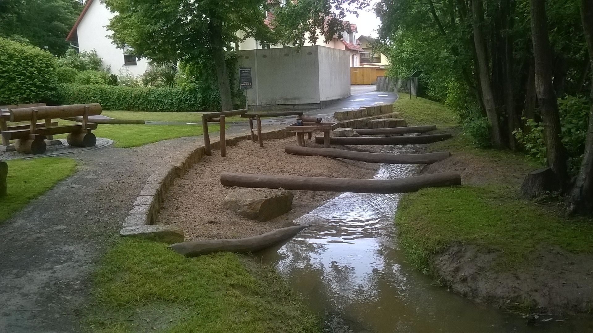 einzelne Baumstämme liegen über einem kleinen Bach