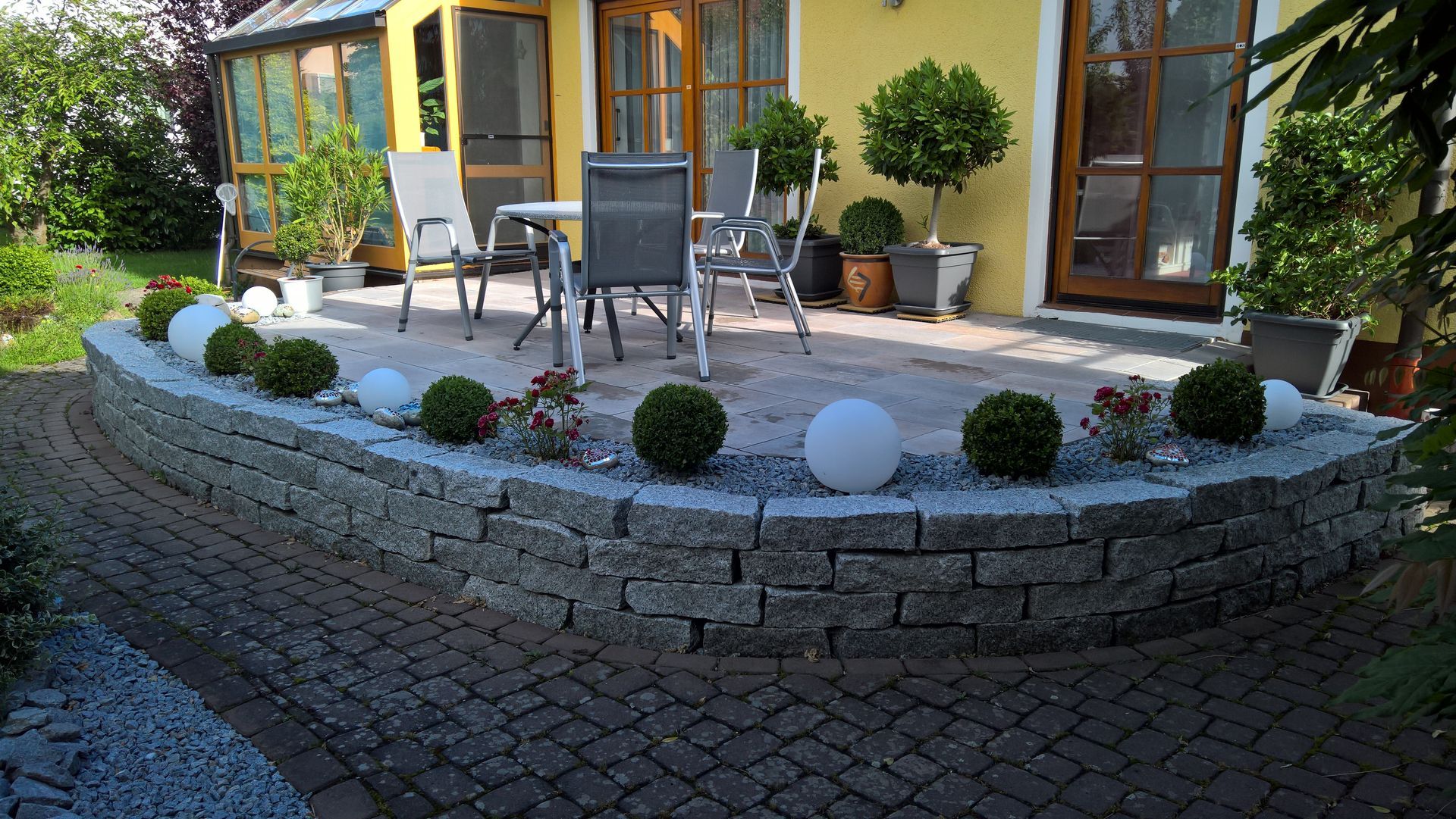 erhöhte Terrasse aus Stein an einem gelben Haus