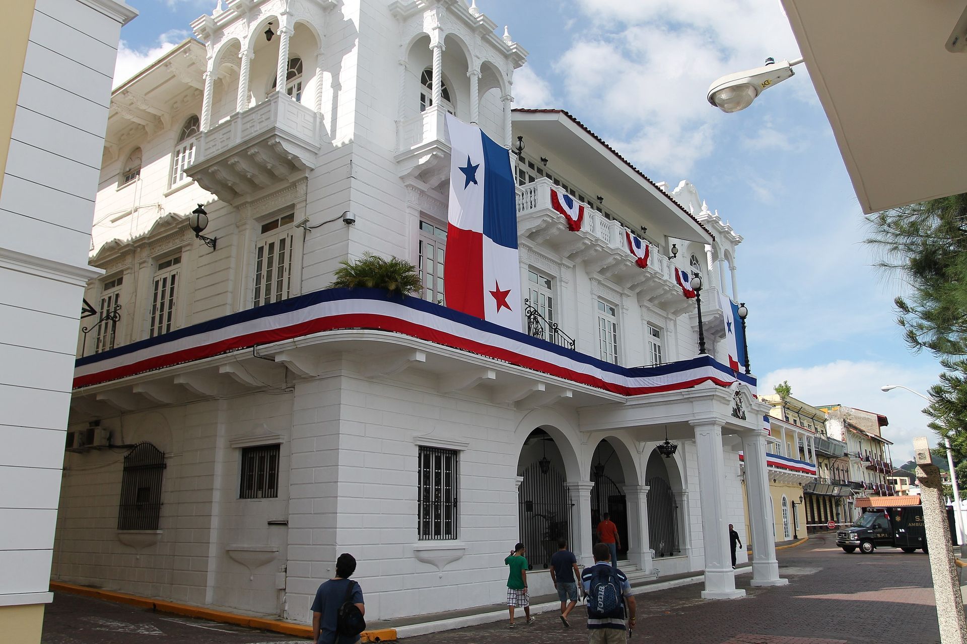 Un edificio blanco con una bandera colgando del balcón.