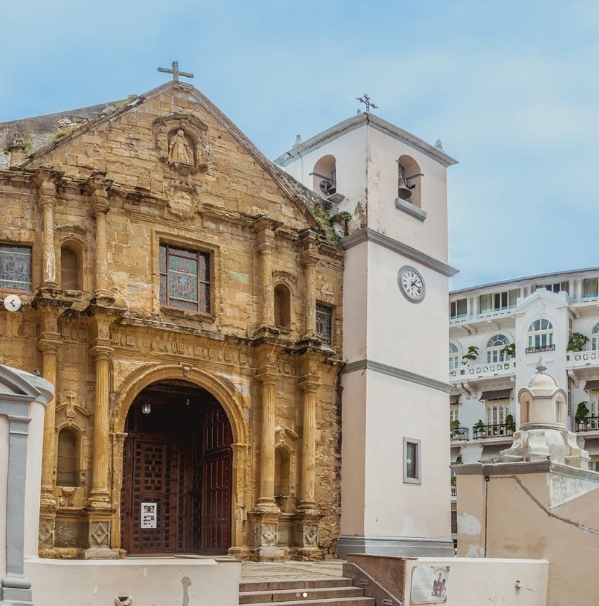 Una iglesia con una torre de reloj y una cruz en la parte superior