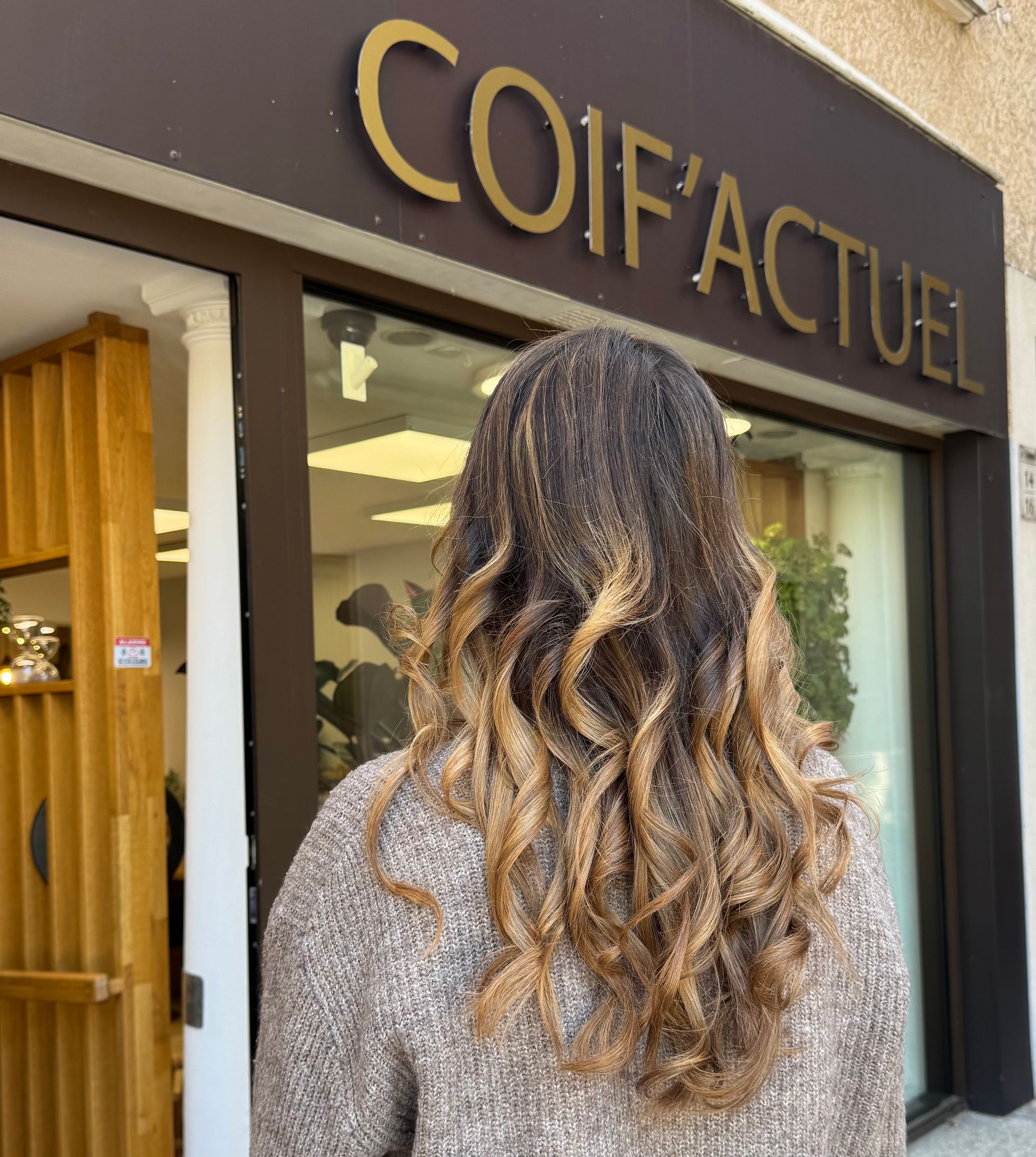 Personne se tenant devant le salon avec de longs cheveux ondulés