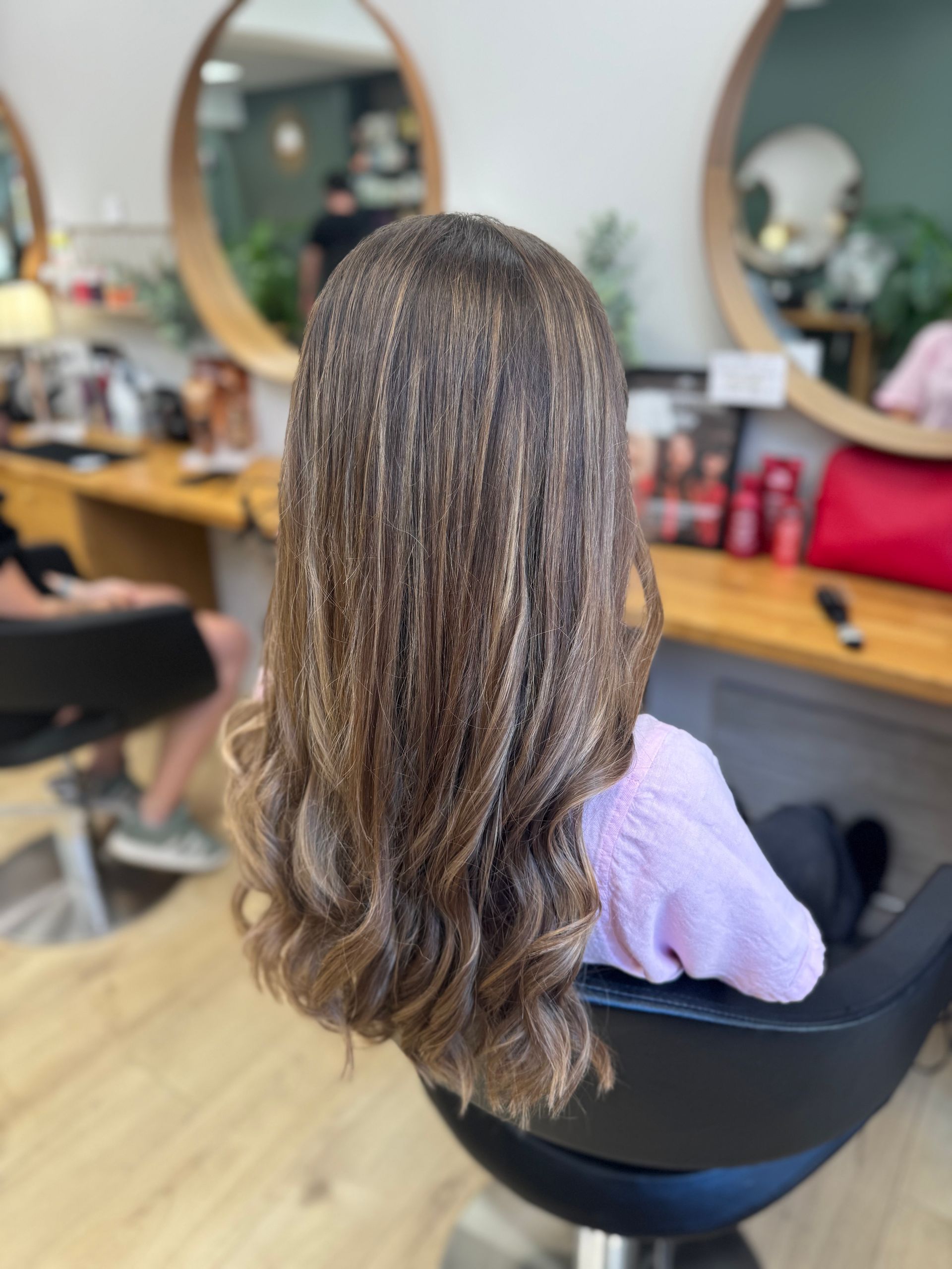 Femme aux longs cheveux ondulés assise sur un fauteuil de salon de coiffure