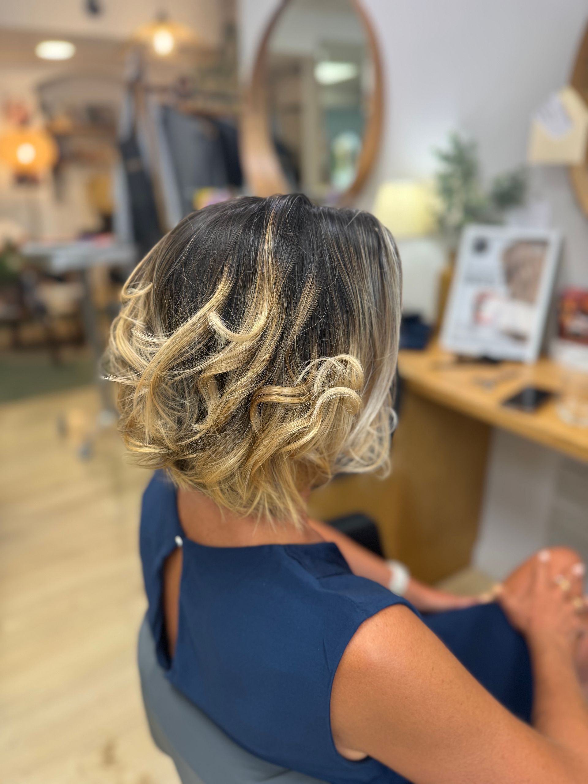Personne aux cheveux blonds bouclés assise dans un fauteuil de salon