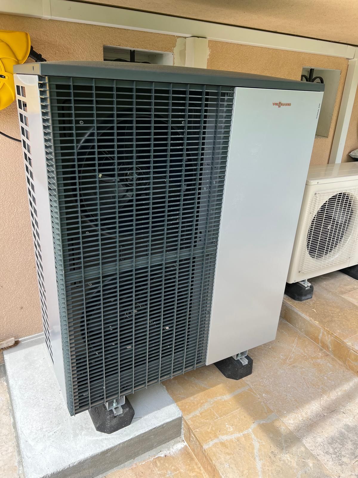 Unité extérieure de pompe à chaleur air-eau installée contre une habitation pour un chauffage performant et économe en énergie.