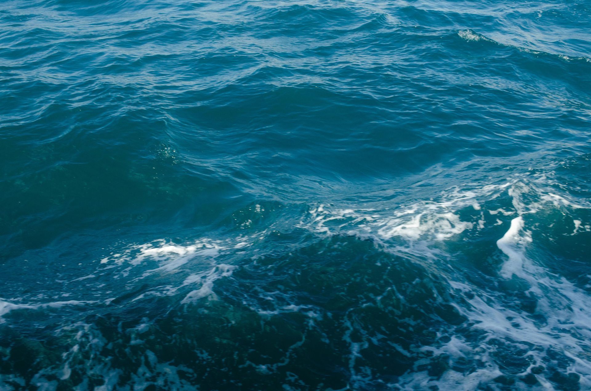 Dunkelblaues Meerwasser mit weißen, schäumenden Wellen.