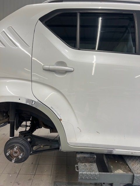 Ein weißes Auto steht auf einer Hebebühne in einer Garage