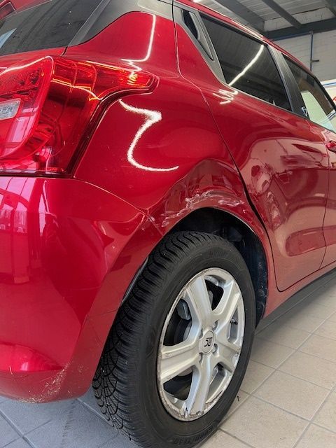 Ein rotes Auto mit einem schwarzen Reifen steht in einer Garage