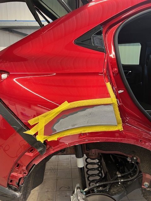 Ein rotes Auto wird mit gelbem Klebeband repariert