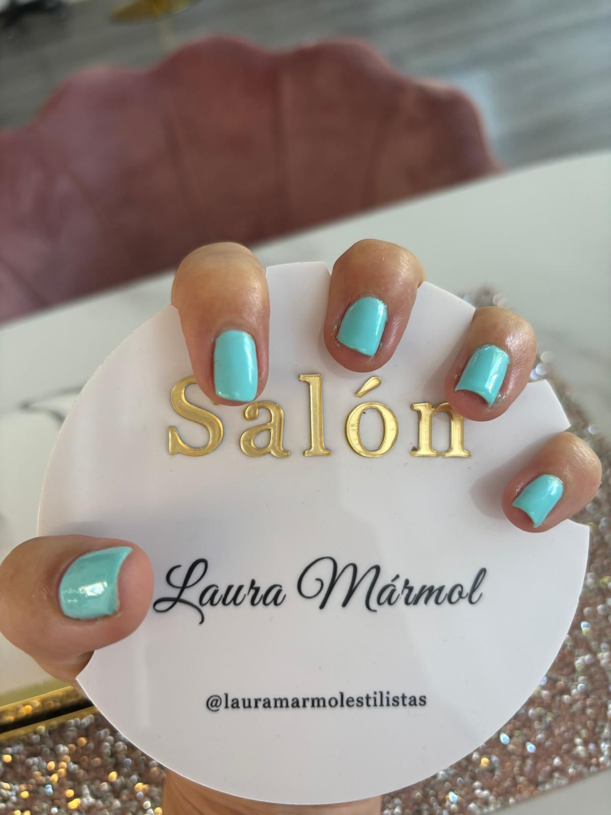 Mano con uñas color turquesa sosteniendo un cartel blanco que dice 