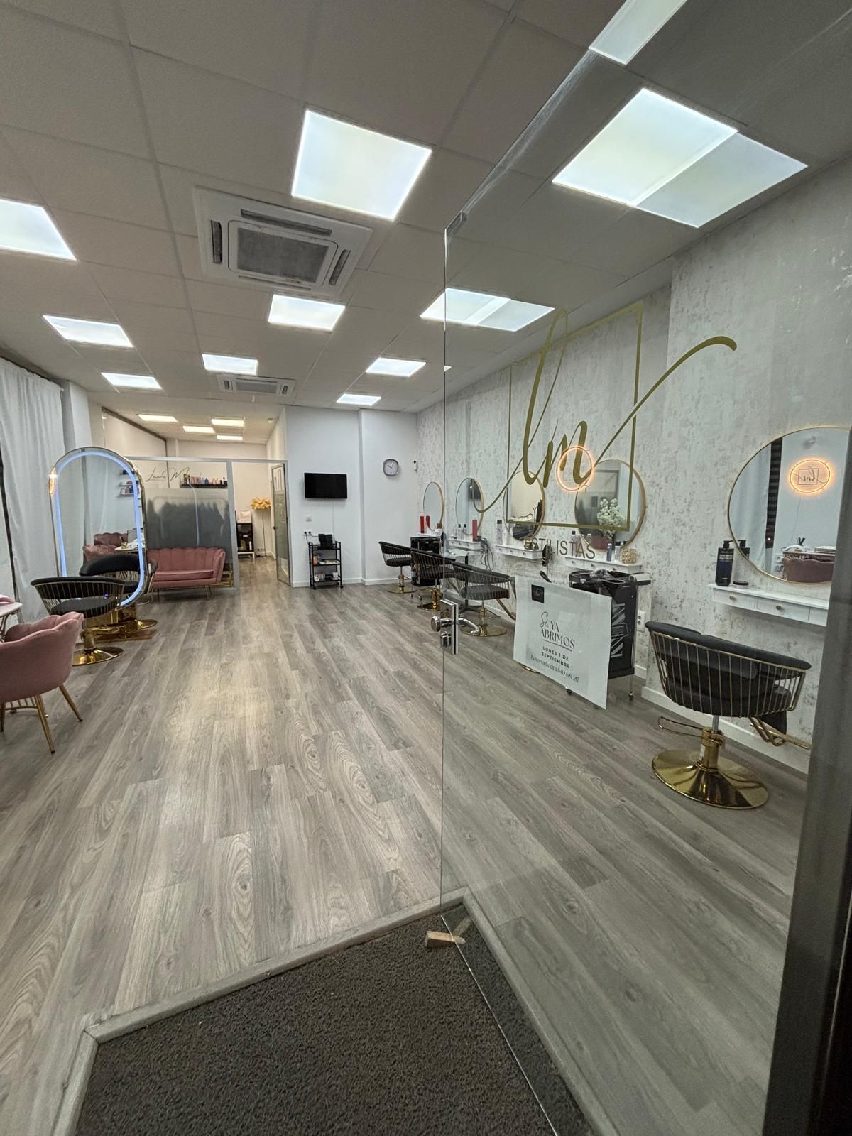 Interior de peluquería con espejos, sillas e iluminación.